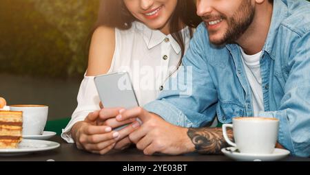Unrecognizable Couple Using Mobile Phone Sitting In Cafe, Cropped, Panorama Stock Photo