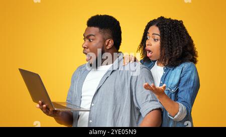 Black couple holding laptop and emotionally reacting to news in internet Stock Photo
