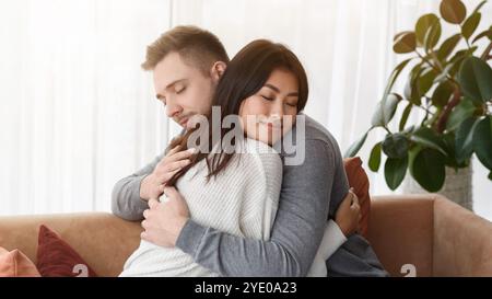 Multicultural Couple Hugging Reconciling After Quarrel At Home Stock Photo
