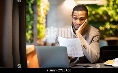 Afro businessman looking at documents with graphs Stock Photo