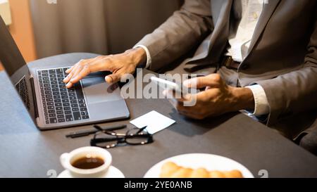 Cropped image of afro guy using phone and computer Stock Photo