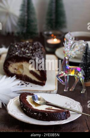 Chocolate roll stuffed with butter cream and pineapple on a Christmas background. Rustic style, selective focus. Stock Photo