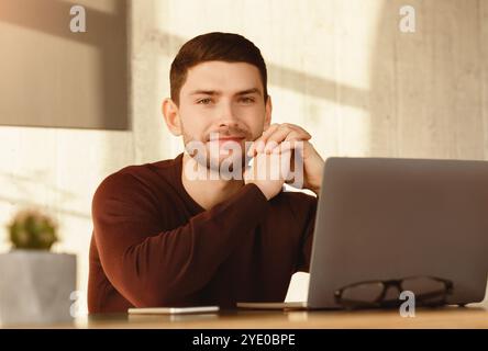 Young Man At Laptop Sitting At Workdesk In Modern Office Stock Photo