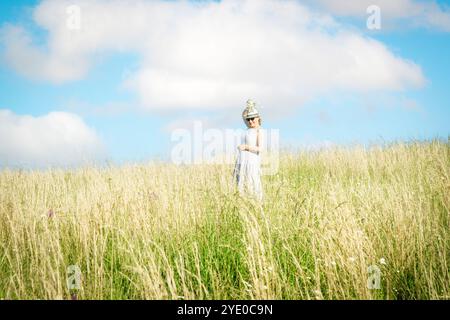 Happy mature woman with wildflowers in a tall grass field on a bright summer day. Stock Photo