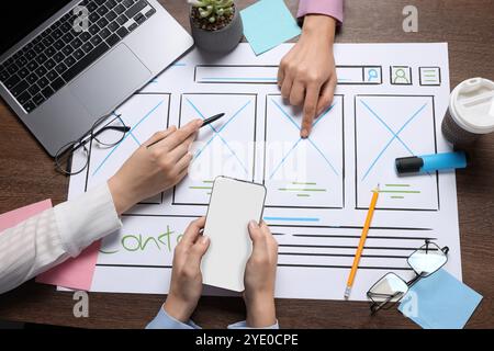 Developing UI design. Designers creating website wireframe on paper at wooden table, top view Stock Photo