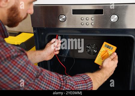 Repairman testing oven element with multimeter, closeup Stock Photo