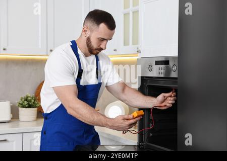 Repairman testing oven element with multimeter in kitchen Stock Photo