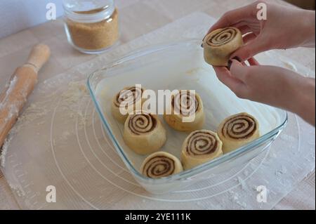 A woman hands putting a piece of roll in a baking dish on a table on a silicone mat Stock Photo