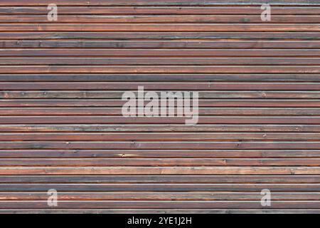 Fine brown wood paneling on the exterior wall of a building. The timber boards are mounted as a house facade. The full frame texture is abstract. Stock Photo