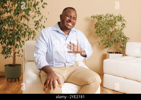 An African American man clutches his chest in pain, possibly having a heart attack or cardiac arrest. The image shows clear signs of distress and an u Stock Photo
