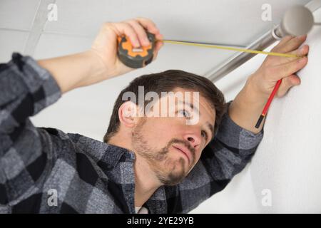 man installing curtain rail above window Stock Photo
