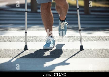 man trying to walk on street with the help crutches Stock Photo