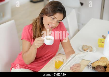 happy woman reading a newspaper and holding a coffee cup Stock Photo