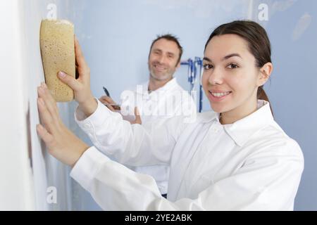female construction worker smoothing wall surface Stock Photo