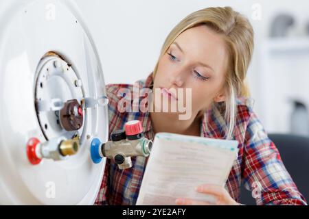 female trainee plumber working on central heating boiler Stock Photo
