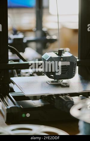 Process of creating 3D printed objects in workshop setting by operating advanced 3D printing machine, with intricate components and working elements set up for precise printing Stock Photo