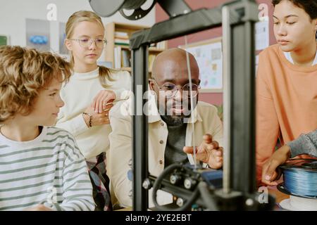 Multiracial group of students and teacher working on project in classroom. Teacher guiding students while engaged in collaborative hands-on activities Stock Photo