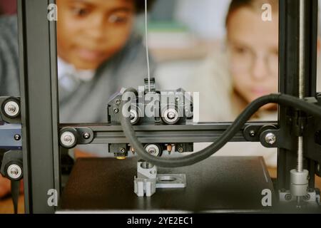 Students observing intricate 3D printing process with focused expressions, showcasing technology in educational environment Stock Photo