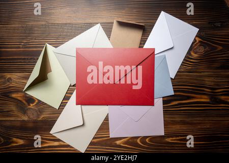 Top view of stack of envelope and postcard on wooden background. The envelopes are of different variation size and colors. Mockup, blank template, cop Stock Photo