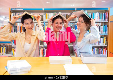Group of Happy Students in Library with Books on Heads Stock Photo