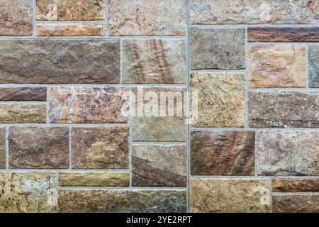 Close-up of masonry made of porcelain stoneware tiles of various sizes and shapes, stylized as antique. Background Stock Photo