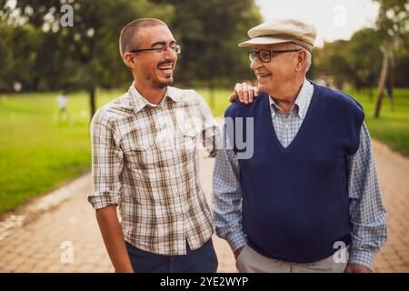 Portrait of happy grandfather and grandson in park. They are walking and having fun. Stock Photo