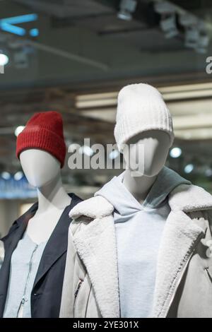 In a retail store, two mannequins are dressed in stylish hats and warm coats, showcasing the winter fashion collection for customers Stock Photo