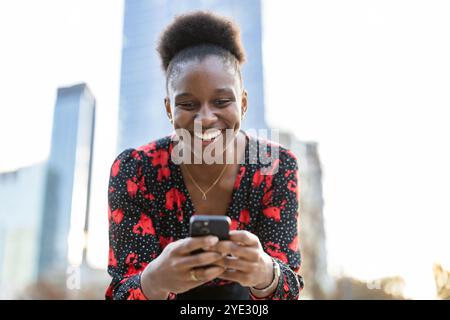 Happy young woman using mobile phone in the city Stock Photo