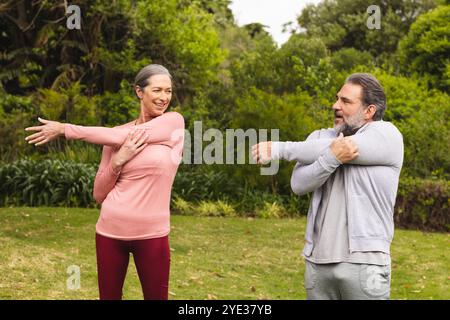 Mature couple stretching arms outdoors, smiling and enjoying exercise together Stock Photo