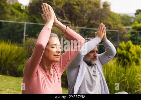 Practicing yoga outdoors, mature couple meditating with eyes closed, feeling peaceful Stock Photo