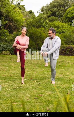 Mature couple practicing yoga together outdoors, enjoying peaceful morning exercise Stock Photo