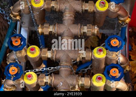 A detailed view of a complex plumbing system featuring multiple valves and fittings connected with pipes, showcasing the intricate engineering outdoors. Stock Photo