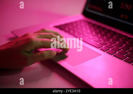 Hand Typing on Laptop with Pink Light Reflection Stock Photo