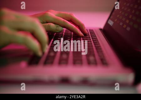 Typing on Laptop with Red Backlighting in Dark Room Stock Photo