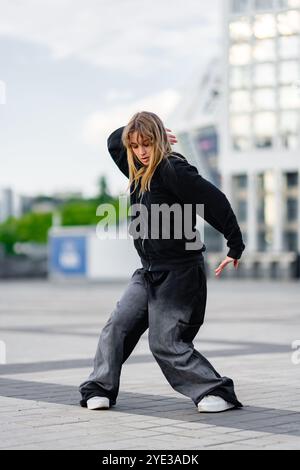 Young dancer practicing street style moves in an urban plaza setting Stock Photo