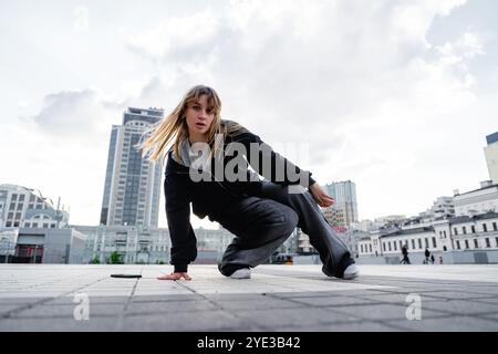 Young dancer practicing breakdancing moves on urban plaza during daytime Stock Photo