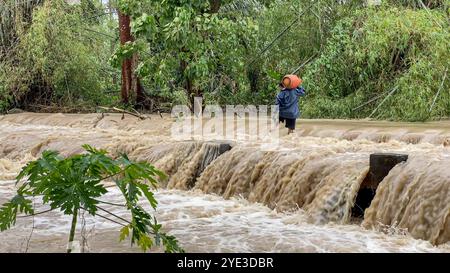 Laguna, Luzon Island, Philippines. Oct 25,2024: Heavy rains turned a small river into a powerful floodwater torrent cutting off the road. Severe Tropical Cyclone Trami (Kristine) aftermath in Philippine archipelago, one of the world's most climate vulnerable regions as the Southeast Asia's country is struck by multiple natural disasters a year. Millions of Filipinos suffered torrential rainfall, floods, strong winds, damages, landslides, electricity/internet outages, evacuation. The deadliest storm killed 145 peoples/37 missing. Many areas remain isolated. Credit: Kevin Izorce/Alamy Live News Stock Photo