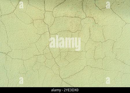 Wall with cracks in green plaster. The wall looks old and worn out Stock Photo