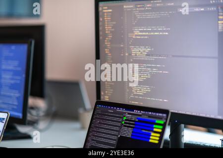 Computer screens running programming code in empty software developing agency office and computers parsing data algorithms in background. Neural Stock Photo