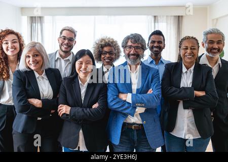 Multi generational workers smiling in front of camera inside business office - Multiracial entrepreneur and teamwork concept - Main focus on man with Stock Photo