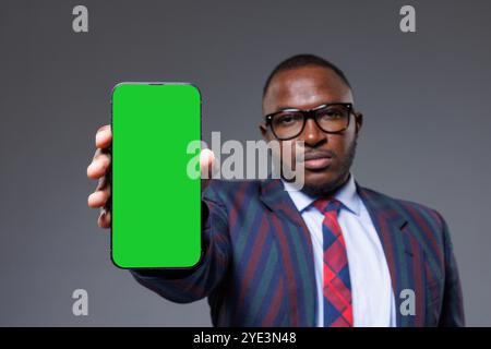 A man holding a green screen phone with a formal attire, perfect for stock footage or creative projects, space for text Stock Photo
