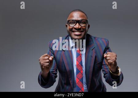 Man business in a suit happy smile with teeth raised hands up clenched fists on a gray background. The joy of winning in business Stock Photo