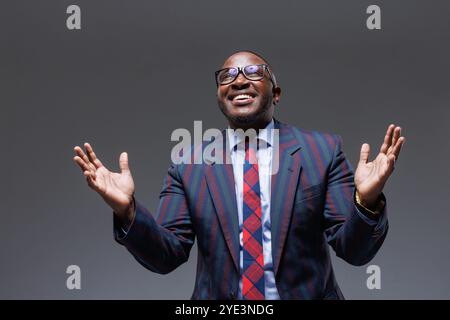 Man business in a suit happy smile with teeth raised hands up clenched fists on a gray background. The joy of winning in business Stock Photo