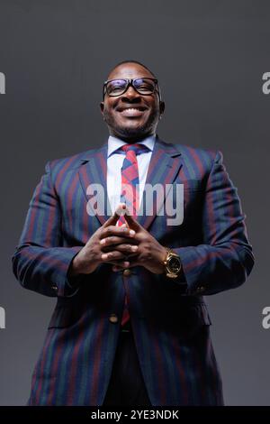 Handsome smiling african american businessman in suit and tie on clean grey background, shot from below, startup concept Stock Photo