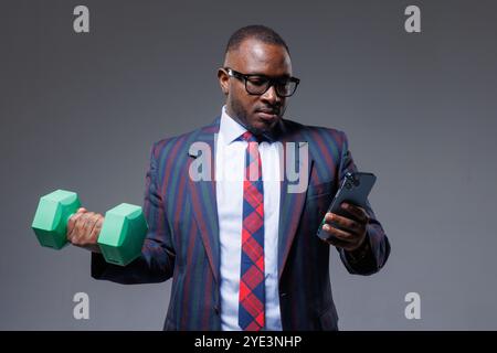 African businessman in suit works online with phone in hand and does sports at the same time, business and sports Stock Photo