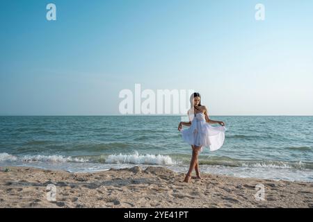 Young woman posing confidently on the sandy beach of Pattaya, Thailand, surrounded by swaying palm trees Stock Photo
