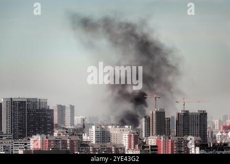 Smoke over the city after air strike, clouds of black smoke blue sky billow over the town dramatic view Stock Photo