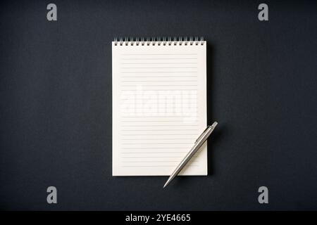 Top view of notebook and ballpoint pen on dark grey background Stock Photo