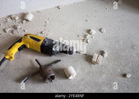 A drill and a wrench are currently laying on the floor, appearing to be forgotten or left behind after completing some work tasks Stock Photo