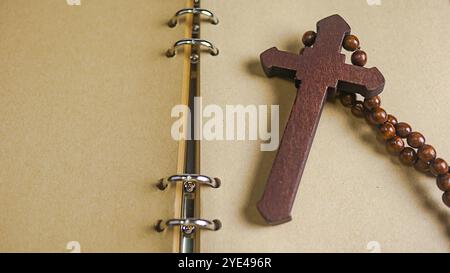 Dark red wooden cross leaning against an old open book symbolizing the spread of Jesus Christs love among Christians reflecting faith devotion and the Stock Photo